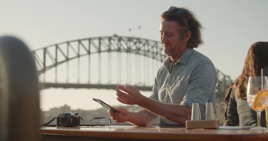 A man uses his phone outside at a table