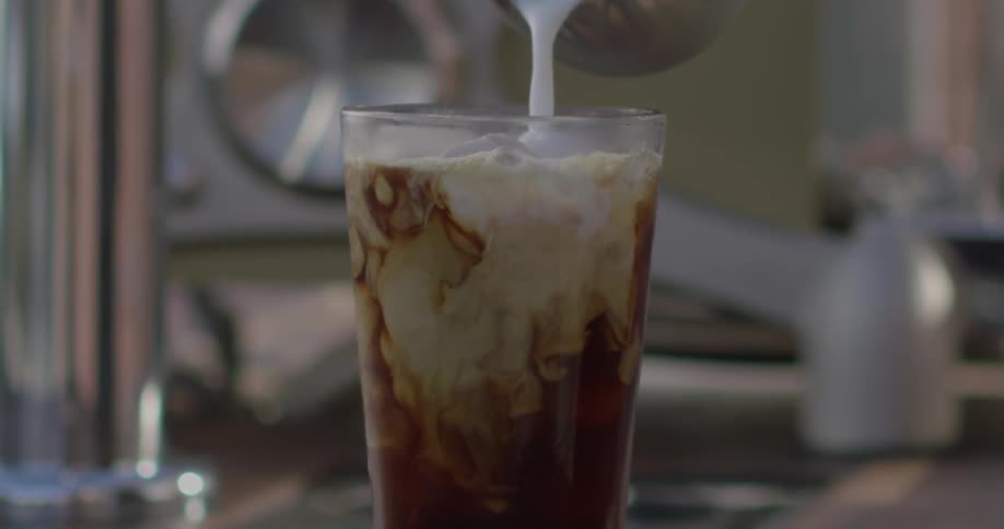 Cream is poured into an iced coffee
