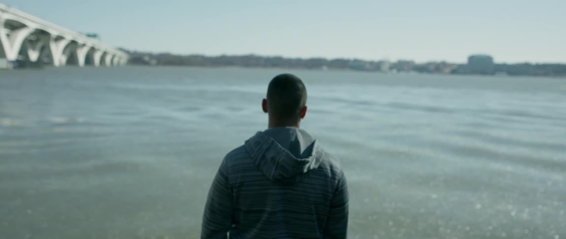 A man stands looking over the bridge
