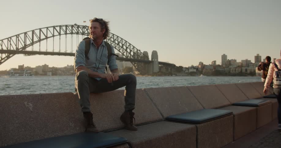 Birds fly over the man sitting near the water