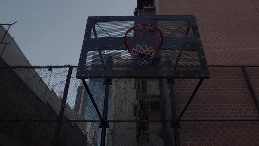 Basketball hoop sits near a fence under a blue sky