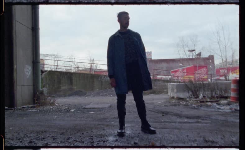 A man stands next to a puddle in a city