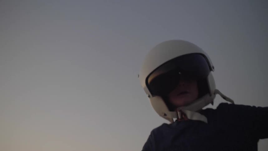 The boy wearing a helmet runs with his arms outspread