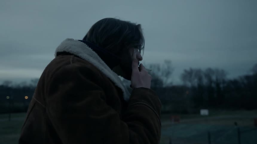 Man smokes a cigarette as he stands in a field