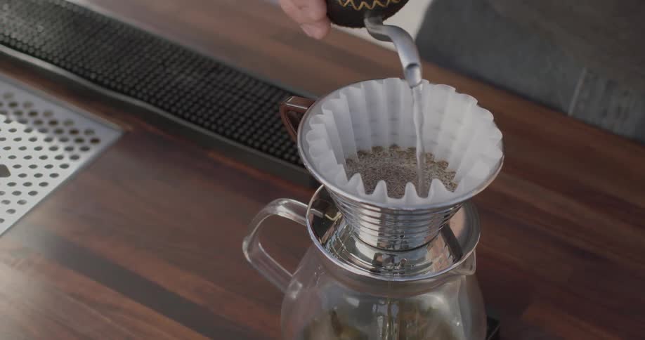 A person pours water into a coffee pot