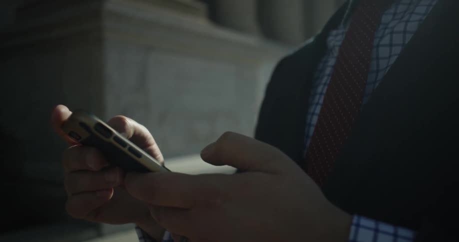 A person is using their phone in front of a stone building