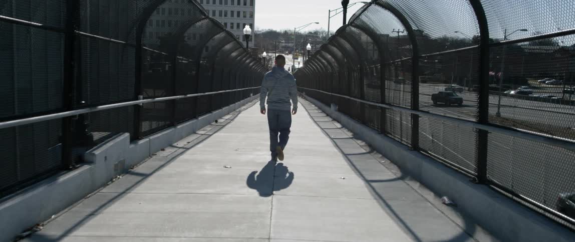 Man walks across urban bridge