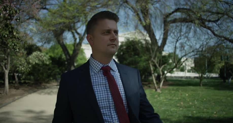 A man in a suit walks outside