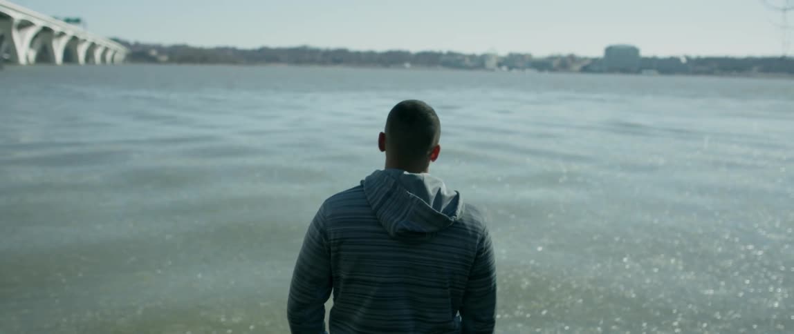 A man stands by the flowing water