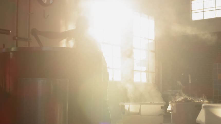 A man is working shoveling out of a vat