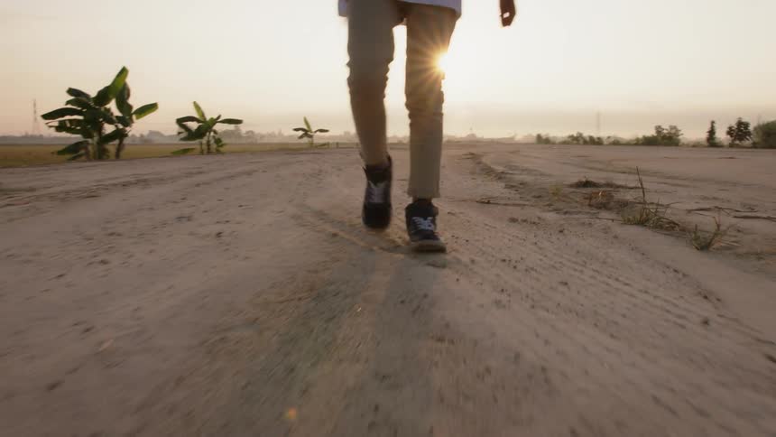 A young man walks outside under the sun