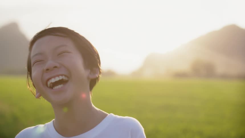A child laughs and makes faces near a field