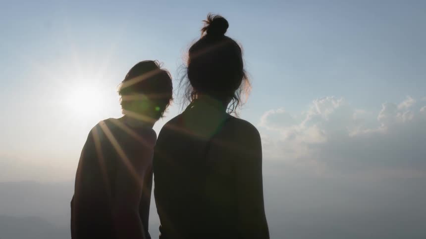 Two people watch the sunrise together