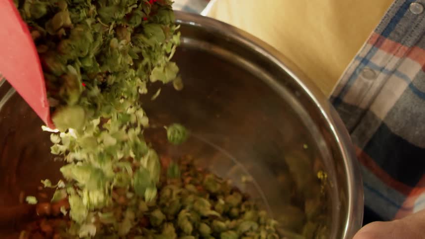 Green vegetables fall from a scoop into a pot