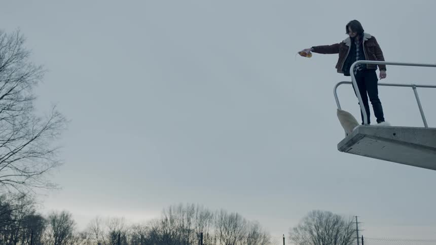 Person on diving board drinks from bottle and pours some liquid down