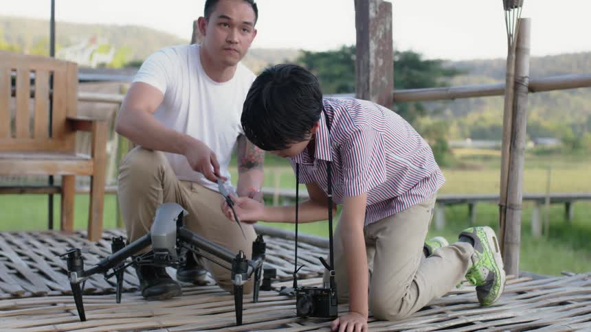 A man and child pull propellers off a drone