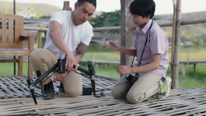 A man and young boy work on a drone