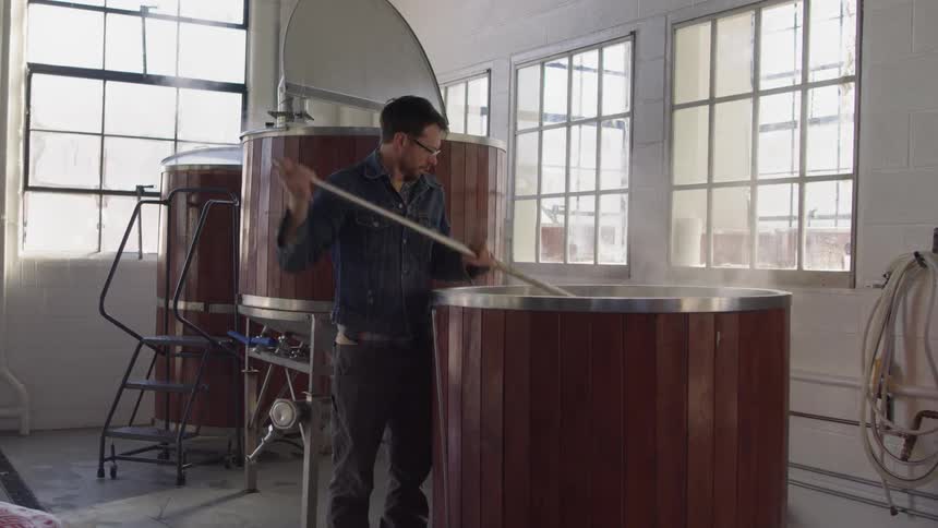 Man stirs a large vat in a brewery
