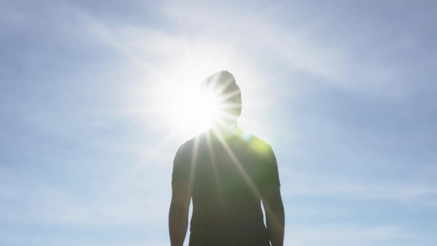 A man stands outside under the sun