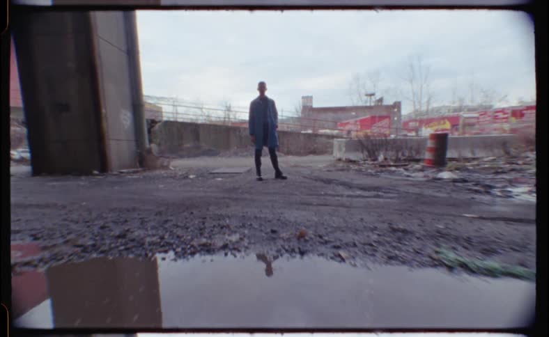 A man stands in the lot by a puddle