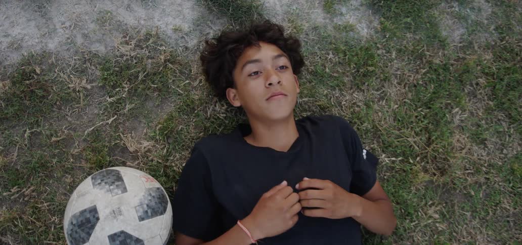 Young boy lays on the ground with a soccer ball next to him