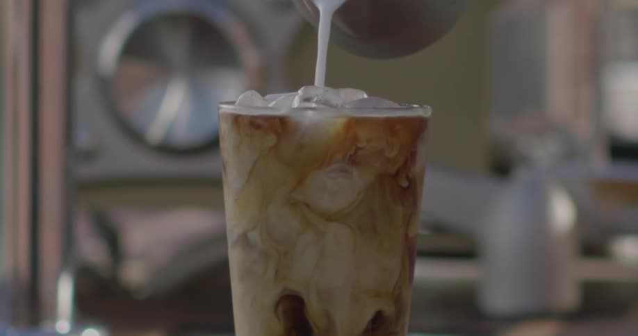 Cream is poured into an iced coffee