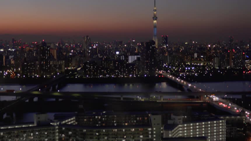 Cars drive on a city road at dusk in Tokyo