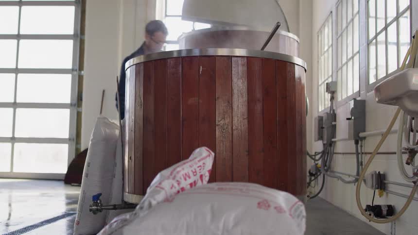A man grabs heavy bags in a brewery