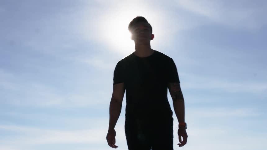 A man walks as the sun shines above him