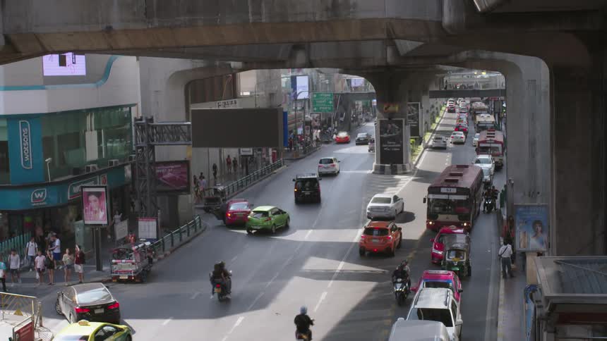 The vehicles and people travel in the city under the train platform