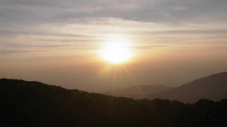 The sun shines brightly over the mountain