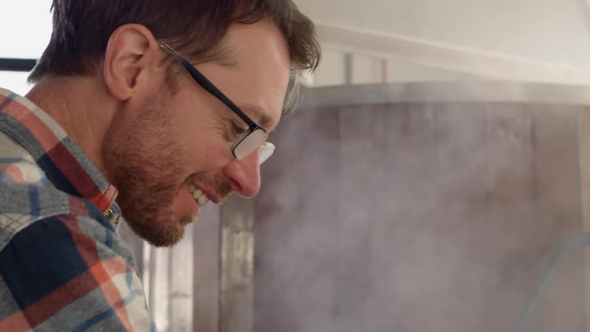 A man smiles while working in a brewery