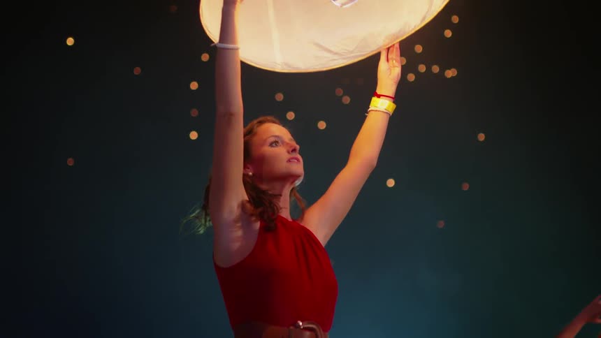 A woman holds up a flaming lantern