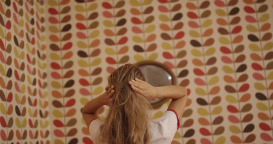 A woman fixes her hair in the mirror
