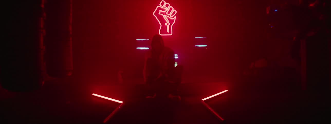 A man sits in a neon lit gym