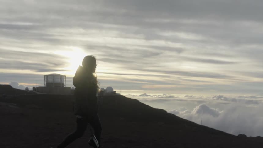 A woman hikes at the top of a mountain