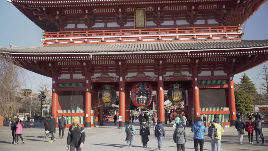 Crowd of people walking in a city square by a traditional Japanese structure
