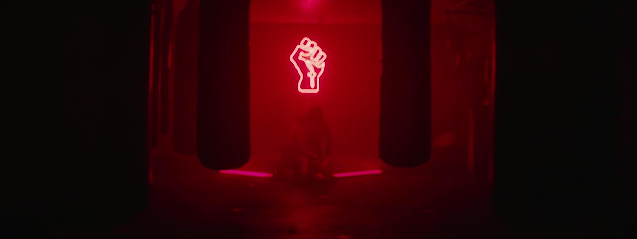 A man is sitting in a red room with heavy weight bags hung around