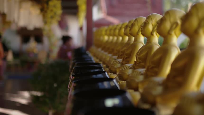 Small gold asian statues are lined up in a market