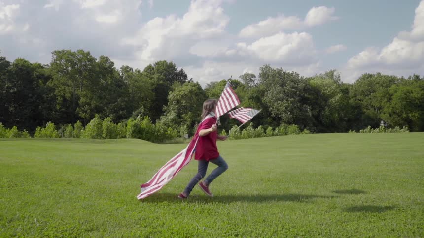 A patriotic child runs outside with american flags