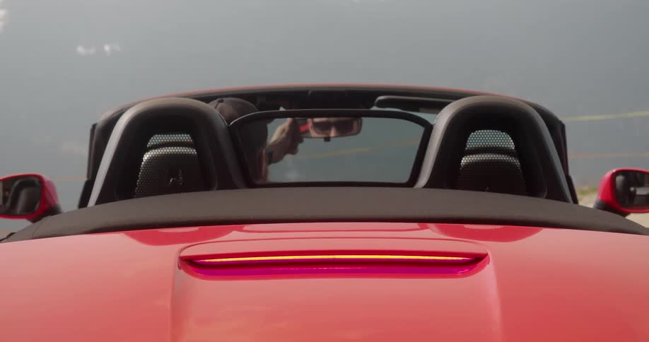 A man adjusts the rear view mirror of his red car