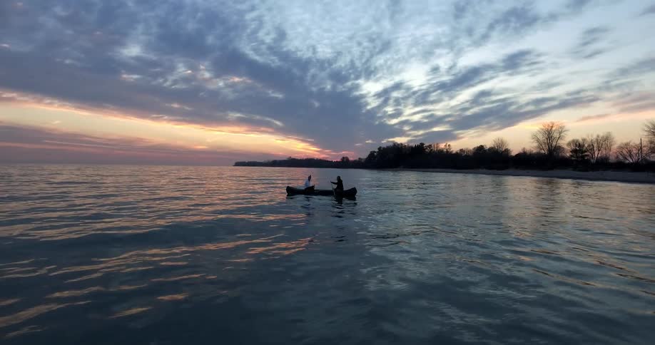 Two people travel in a canoe at dusk