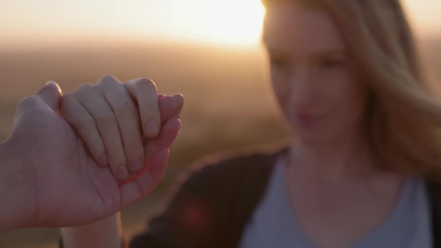 A woman holds a person's hand on a windy day