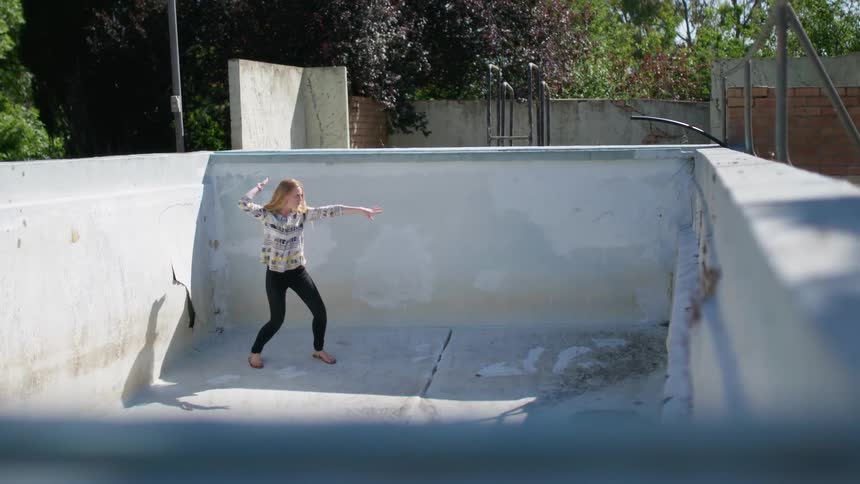 A woman is dancing around in the empty pool