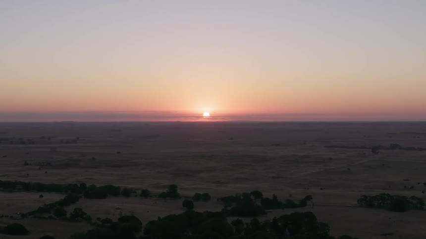 The sun sets behind the open field
