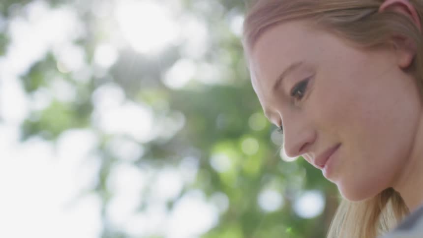 A woman looks down under a tree