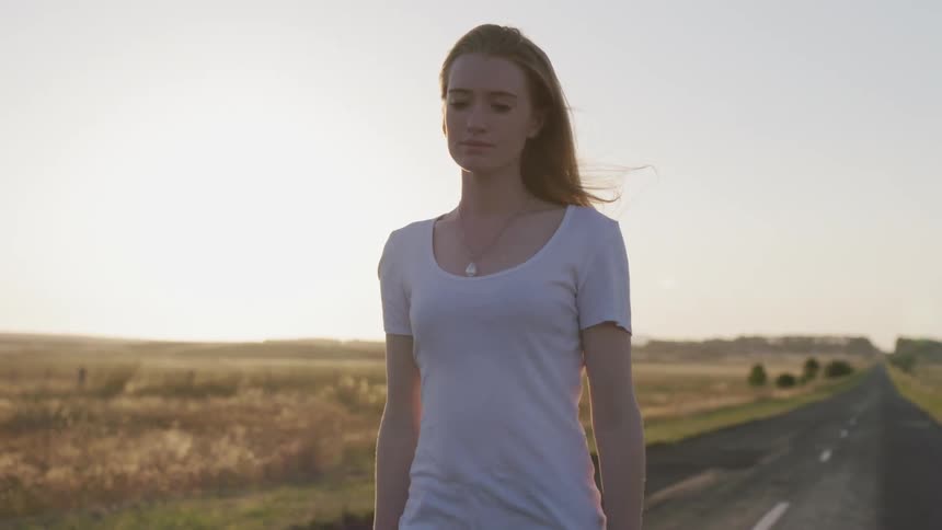 A woman walks next to a grass field