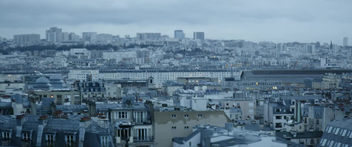 Smoke billows from chimneys in a city skyline on a cloudy day