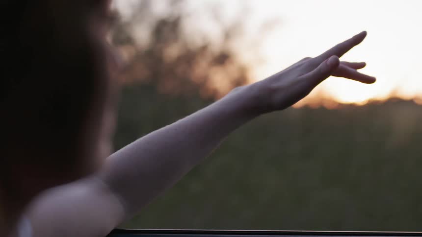 A woman sticks her hand out of a car