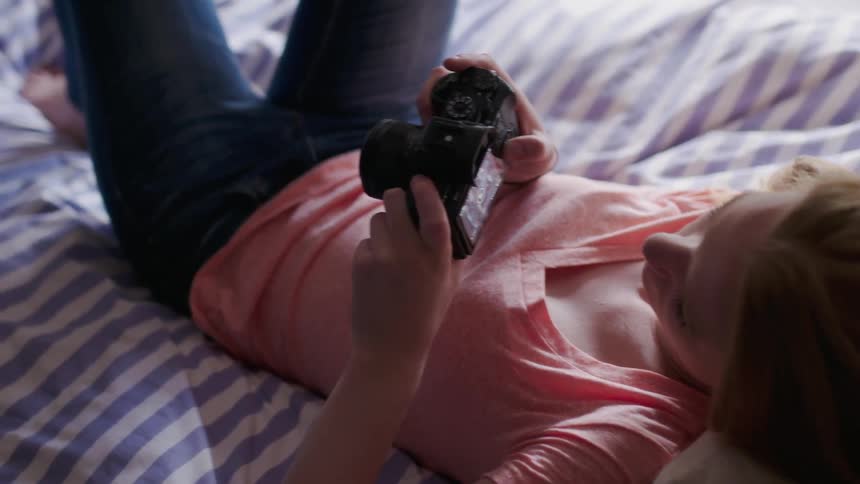 A woman is using her camera in bed
